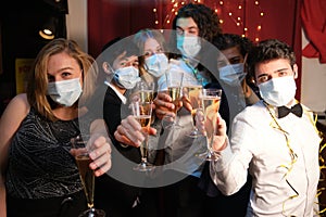 Group of fiends wearing face masks at a Christmas party looking at the camera in a bar
