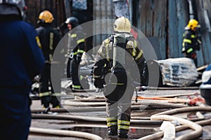 Group of fire men in protective uniform during fire fighting operation in the city streets, firefighters brigade with the fire