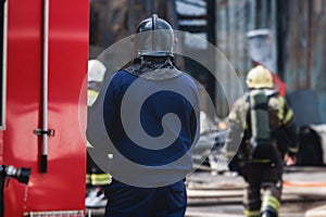 Group of fire men in protective uniform during fire fighting operation in the city streets, firefighters brigade with the fire