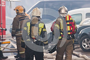 Group of fire men in protective uniform during fire fighting operation in the city streets, firefighters brigade with the fire