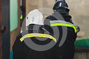 Group of fire men in protective uniform during fire fighting operation in the city streets, firefighters brigade with the fire