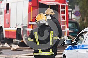 Group of fire men in protective uniform during fire fighting operation in the city streets, firefighters brigade with the fire