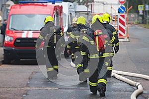 Group of fire men in protective uniform during fire fighting operation in the city streets, firefighters brigade with the fire