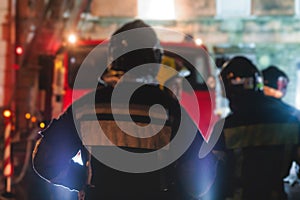 Group of fire men in protective uniform during fire fighting operation in the night city streets, firefighters brigade with the