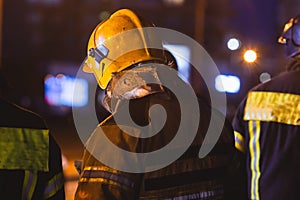 Group of fire men in uniform during fire fighting operation in the night city streets, firefighters with the fire engine truck
