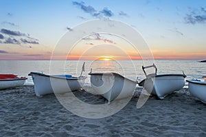 A group of fishing boats on the seashore on the sands of a beach as the sunset . Mediterranean sea boats