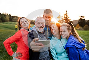 A group of fit and active people resting after doing exercise in nature, taking selfie.