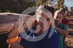 Group of fit women carrying a heavy wooden log during obstacle course training