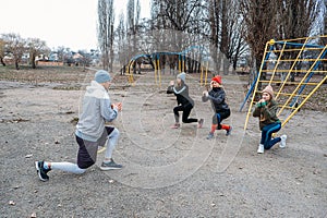 Group fitness classes outdoors. Organized gym classes set up in public parks. Three women and man training together in the public