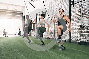 Group fitness is the motivation you need to get in shape. a fitness group doing high knees while working out at the gym.