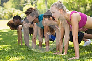 Group of fitness people doing push ups in park