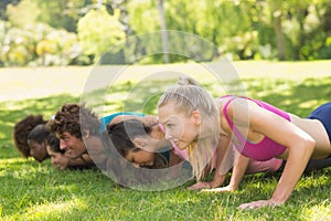 Group of fitness people doing push ups in park