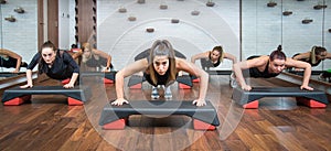 Group of fitness women doing push ups on aerobic stepper in gym