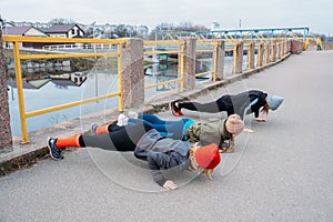 Group fitness workout classes outdoors. Organized gym classes set up in public parks. Three women training together in