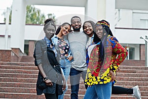 Group of five african college students spending time together on campus at university yard. Black afro friends studying. Education