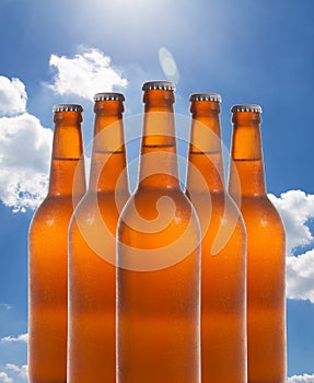 A group of five beer bottles in a diamond formation on sky background.