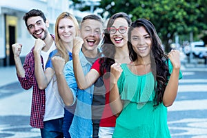 Group of five cheering international young adults in line