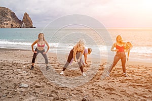 A group of five female friends are doing exercises on the beach. Beach holiday concept, healthy lifestyle