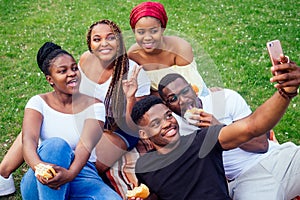 Group of five friends female and male taking selfie on camera smartphone and having fun outdoors lifestyle near lake