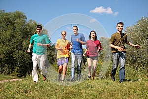 Group of five friends in multicolor shirts runs