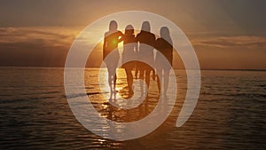 Group of five happy people sits on background of empty sunset beach. Travel or sea vacations concept