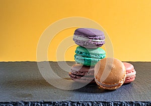 Group of five macaroons of different colours arranged on top of each other with a plain coloured background