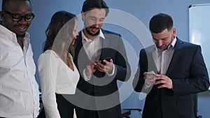 Group of five multiracial business people standing and using smartphones