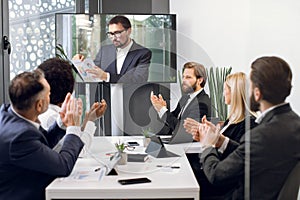 Group of five skillful multiethnical businesspeople clapping hands and looking at screen, having video conference in