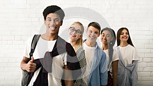 Group of Five Smiling Teenagers Standing Together Against White