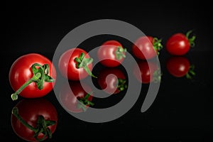 Red cherry tomato isolated on black glass