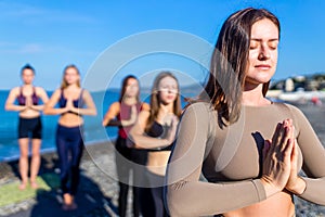 group of five women practicing yoga assans in morning beach . only girls session