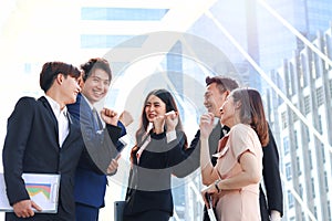 Group of five young Asian cheerful businesspeople raising fist hands up for celebrating success, businessman and woman cheer up