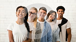 Group of Five Young Friends Smiling Together Against White Wall