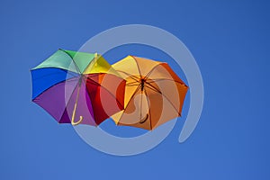 Group of flying umbrellas on blue background, ready for the rain, wallpaper background, bright various colors