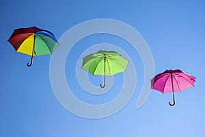 Group of flying umbrellas on blue background, ready for the rain, wallpaper background, bright various colors