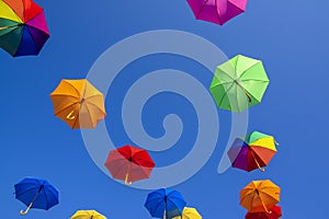 Group of flying umbrellas isolated on blue background, ready for the rain, wallpaper background, bright various colors