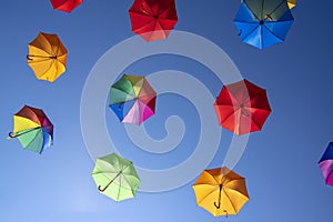 Group of flying umbrellas isolated on blue background, ready for the rain, wallpaper background, bright various colors