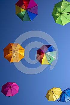 Group of flying umbrellas isolated on blue background, ready for the rain, wallpaper background, bright various colors