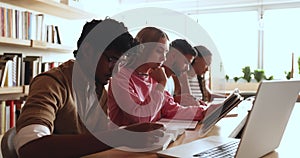 Group of focused multiethnic schoolboys and schoolgirls studying in library