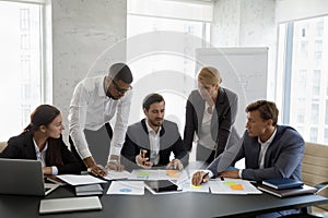 Group of focused young serious multiracial colleagues doing paperwork.