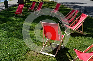 Group of folding wooden hammock chairs on the lawn in foot in the alley in front of restaurant by the river on waterfront. the cyc