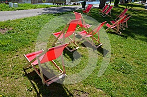 Group of folding wooden hammock chairs on the lawn in foot in the alley in front of restaurant by the river on waterfront. the cyc