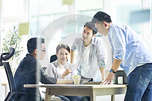 Group of four asian teammates working together discussing business in office