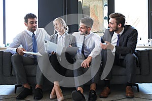 Group of four business people sitting on sofa. They couldn`t be happier about working together