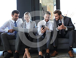 Group of four business people sitting on sofa. They couldn`t be happier about working together