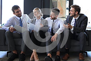 Group of four business people sitting on sofa. They couldn`t be happier about working together