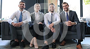 Group of four business people sitting on sofa. We`re the team you need if you want to succeed