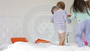 Group Four Children Playing Ring-Around-The-Rosy On Parents Bed
