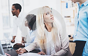 Group of four coworkers discussing business project in office. Beautiful woman talking with colleague. Horizontal, blurred