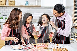 Group of four Diverse Family, Asian and Arab Preschool kid person make Cake cooking in kitchen, Father Mother teaching small cute